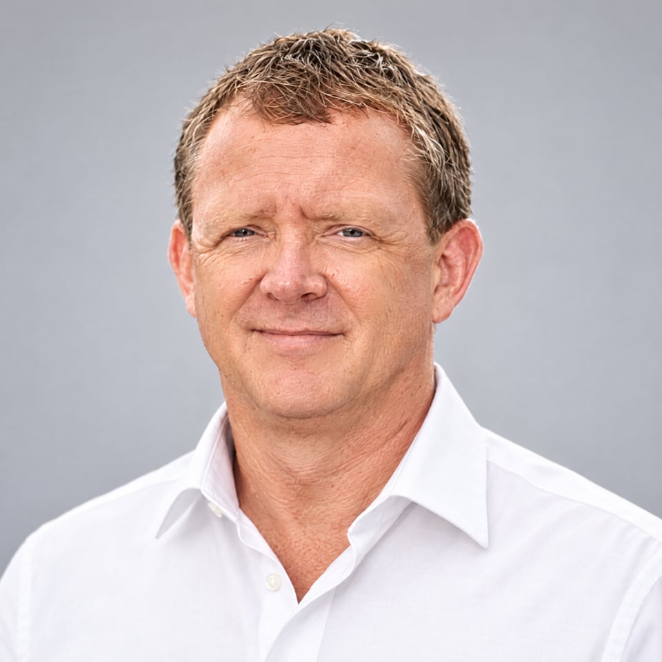 Portrait of Paul Lloyd, founder of Pixel By Hand, in a white shirt against a grey background